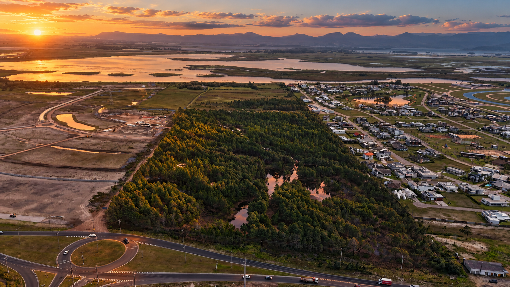 Vista aérea de Atlântida Sul ao pôr do sol, com lagoas, mata e condomínios